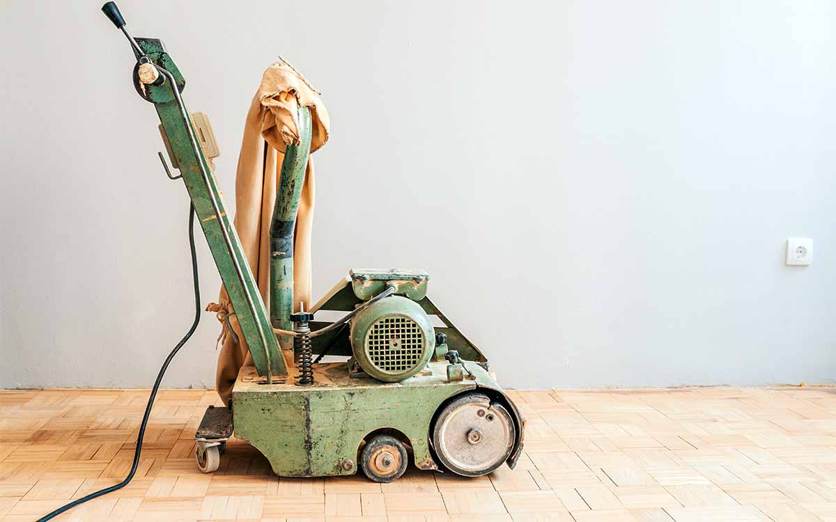 Professionelle Holzboden-Schleifmaschine steht auf einem alten Parkettboden.